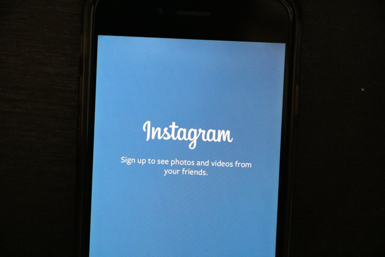 Gros plan sur un smartphone affichant l’écran d’accueil de l’application Instagram, invitant les utilisateurs à s’inscrire.